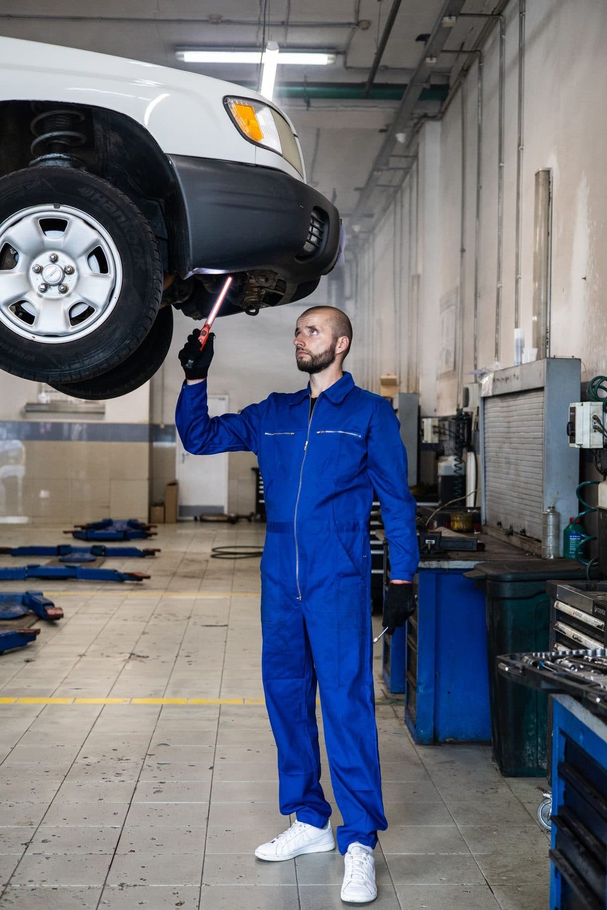 RMG Motors technician working under a vehicle raised on a two-post ramp in the Bittern Road workshop
